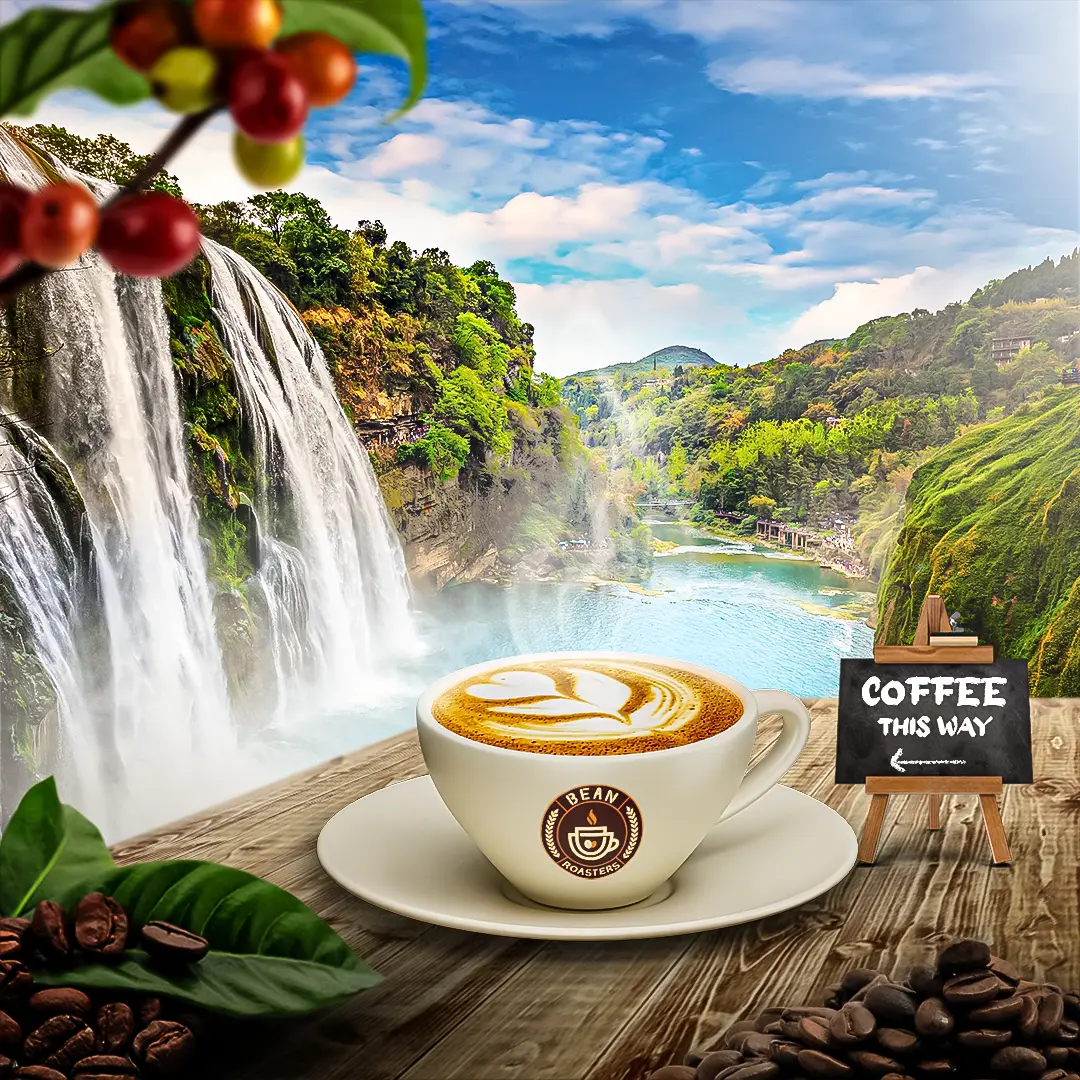 A cup of coffee with leaf-patterned latte art on a wooden deck overlooking a lush, scenic waterfall, representing the brand's natural inspiration.